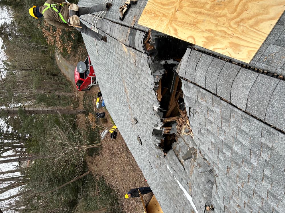 A WCC member walk atop a roof that has been damaged by Hurricane Helene.