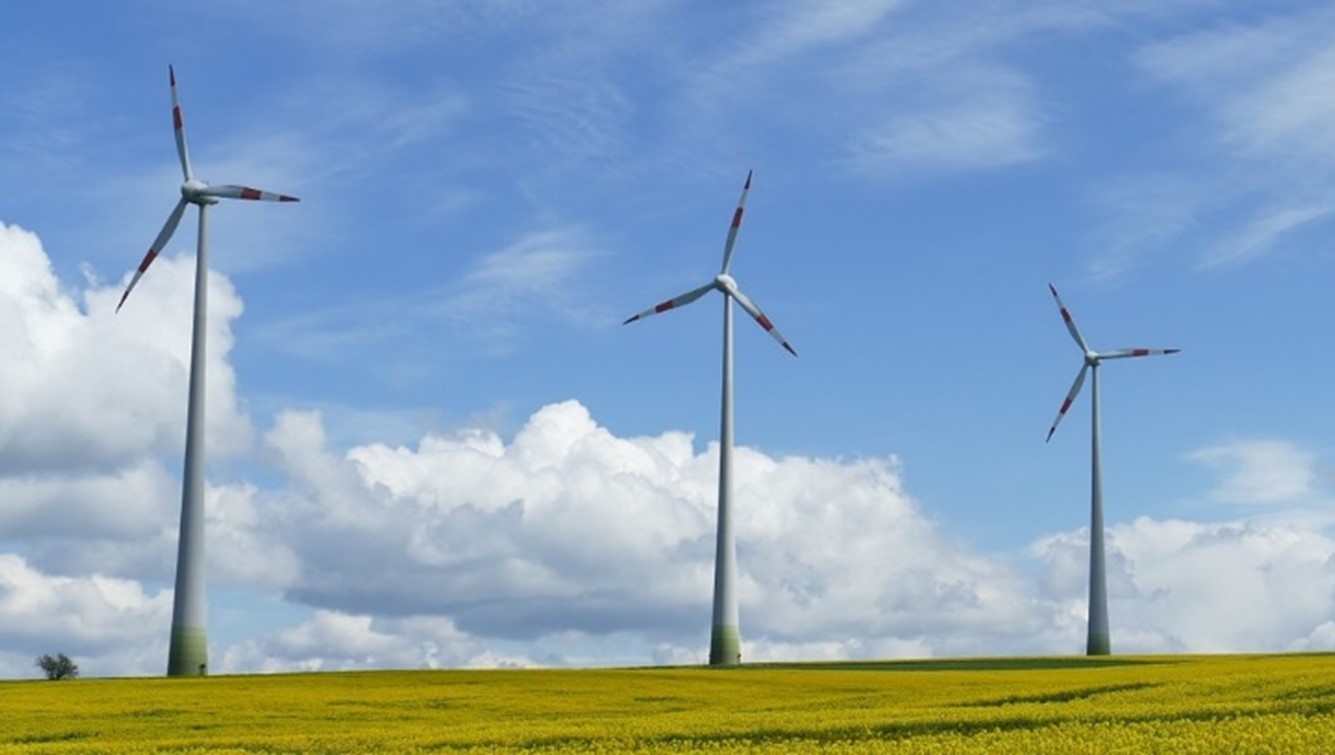Three wind turbines across a grassy field