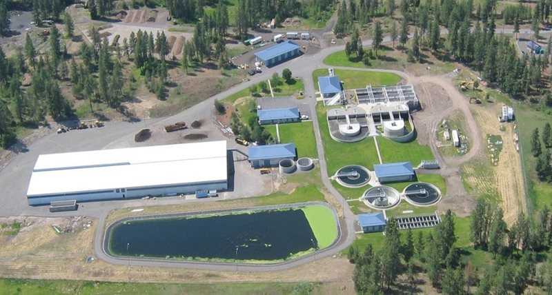 Aerial view of the City of Cheney wastewater treatment facility, including buildings, settling ponds, and a lagoon, with roads surrounding and trees