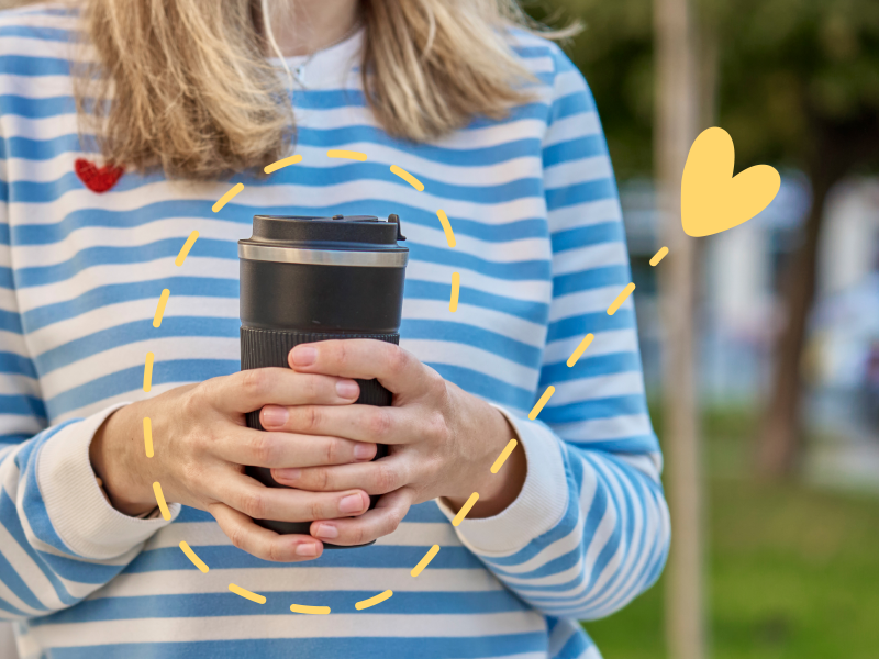 A person in a blue striped shirt holds a reusable coffee cup