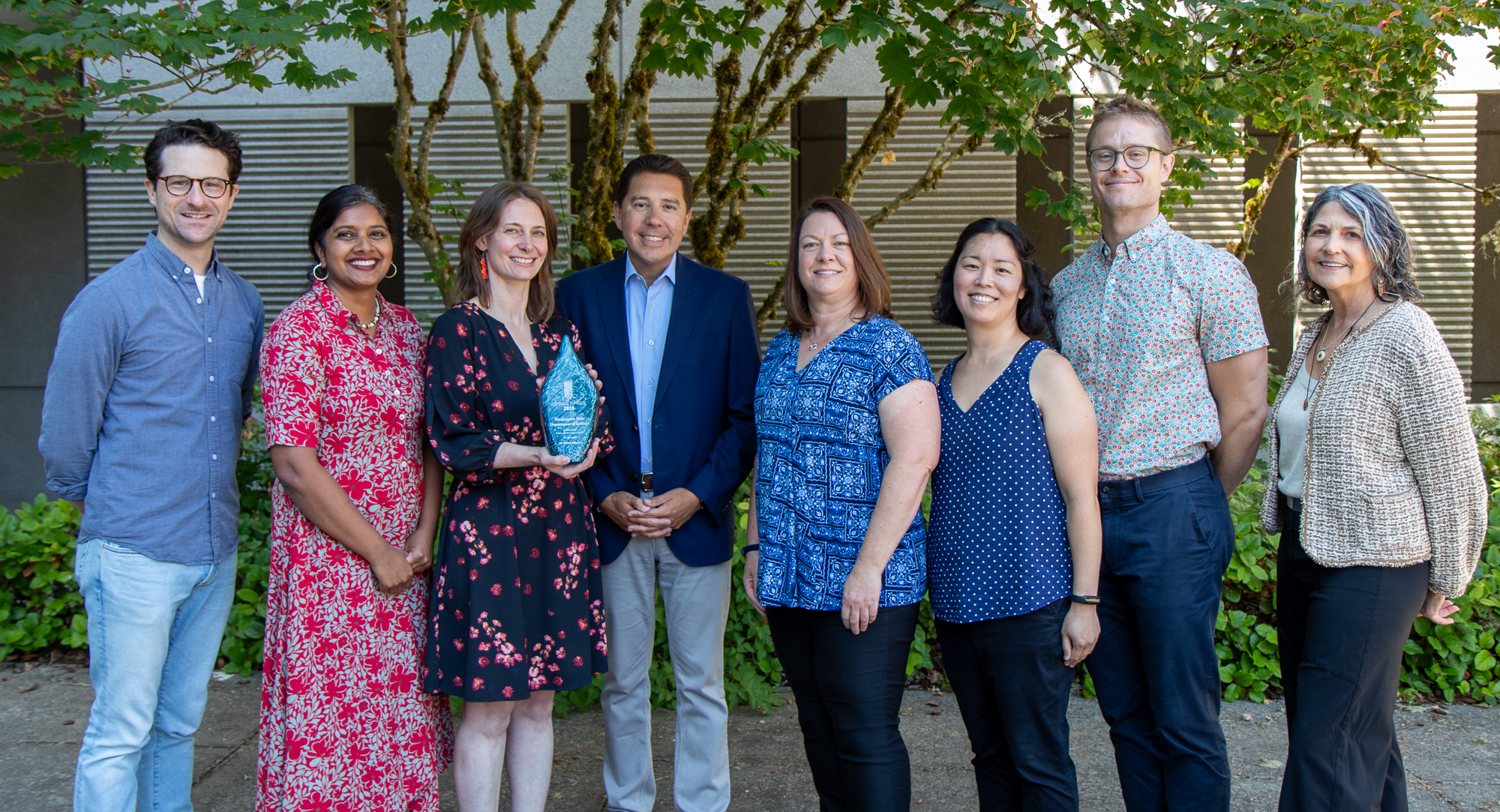 Eight Ecology employees, including Ecology Director Casey Sixkiller gathered to show award statue
