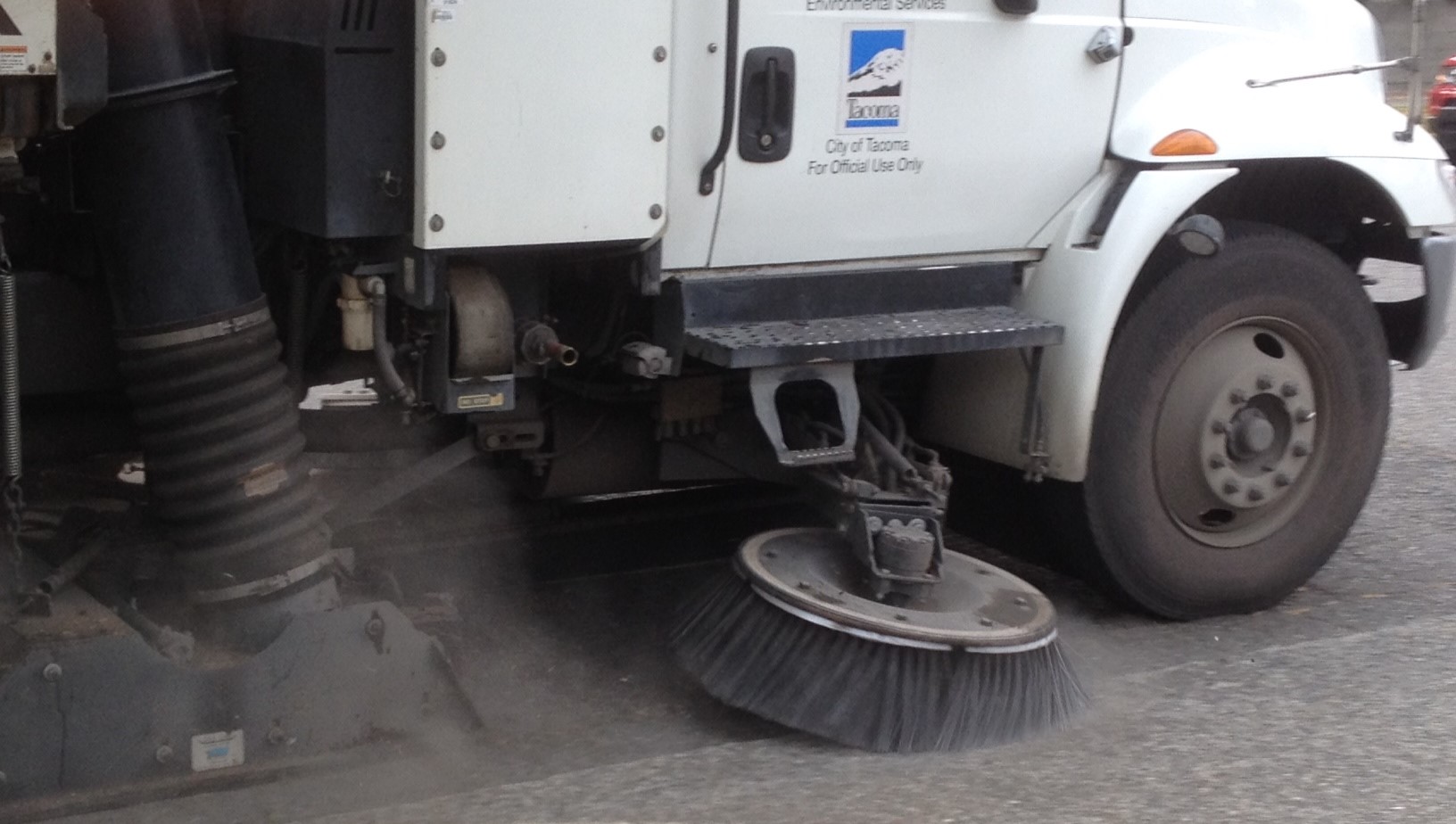 close up of street sweeper brush on road