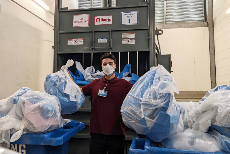 Harborview Medical Center WASI intern holding two clear plastic bags of blue wrap for recycling.
