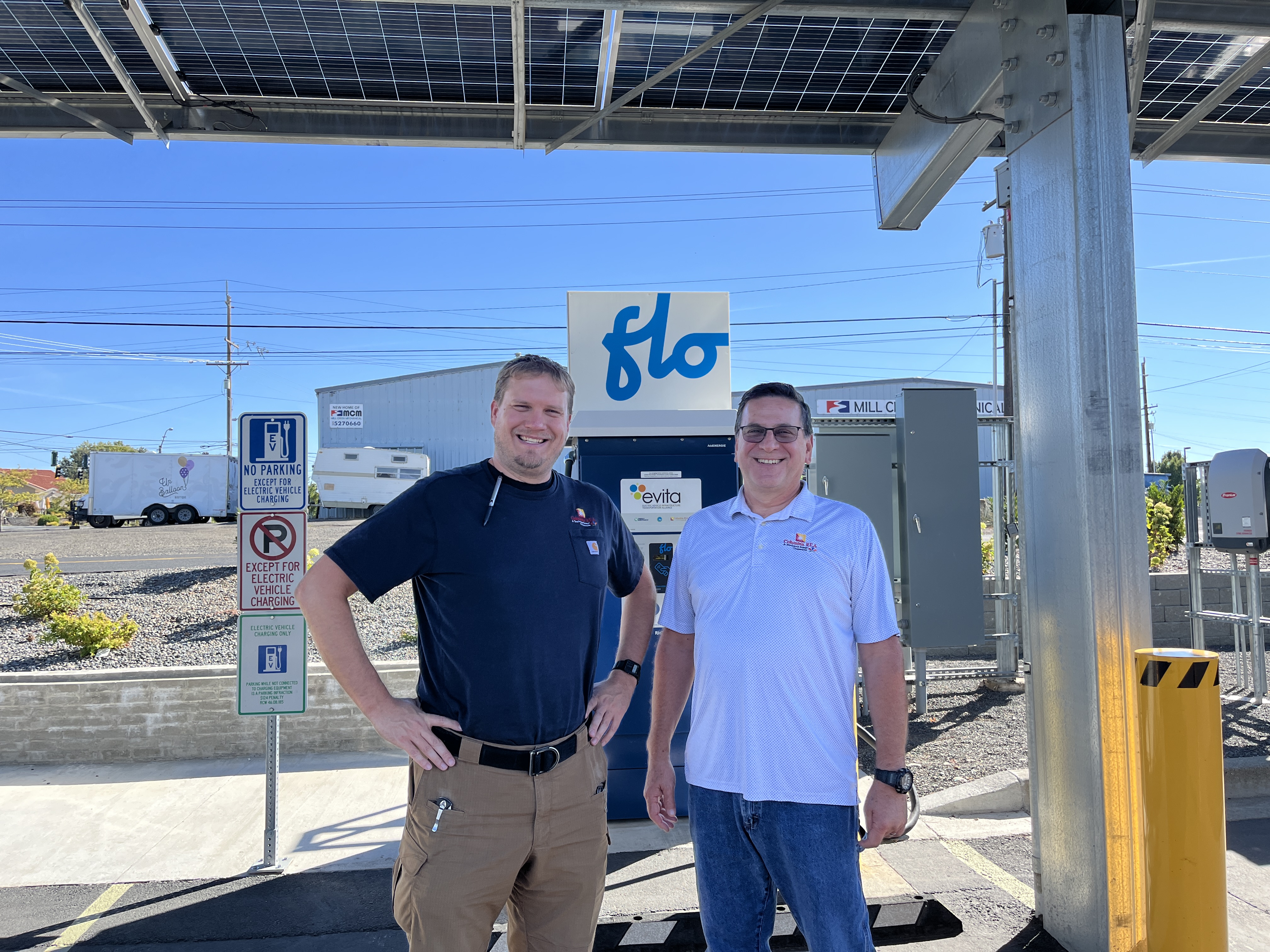 Two people from Walla Walla standing beside an electric car charger