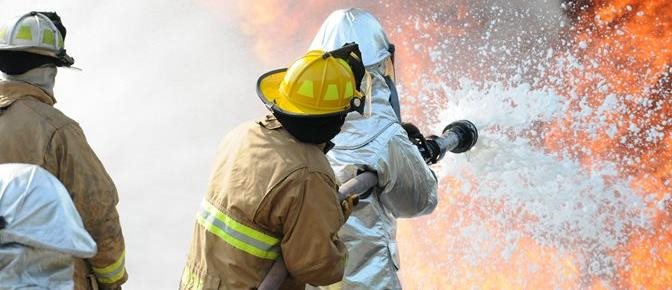 firefighters spraying foam on a fire