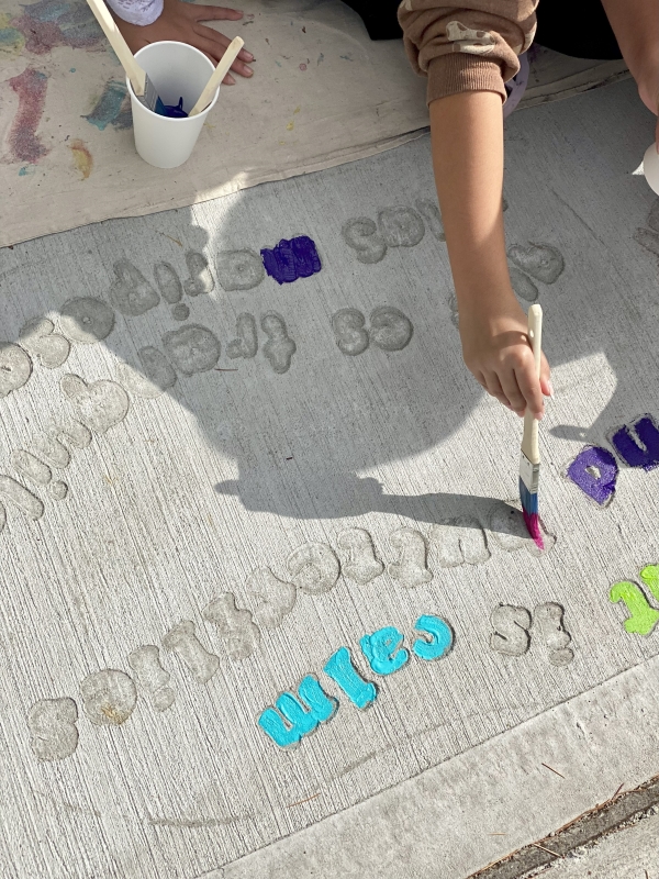 An elementary school student painting sidewalk art